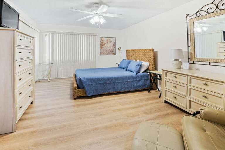 Bright, airy bedroom with woven bed frame, ample storage, and cozy seating. Designed for comfort and