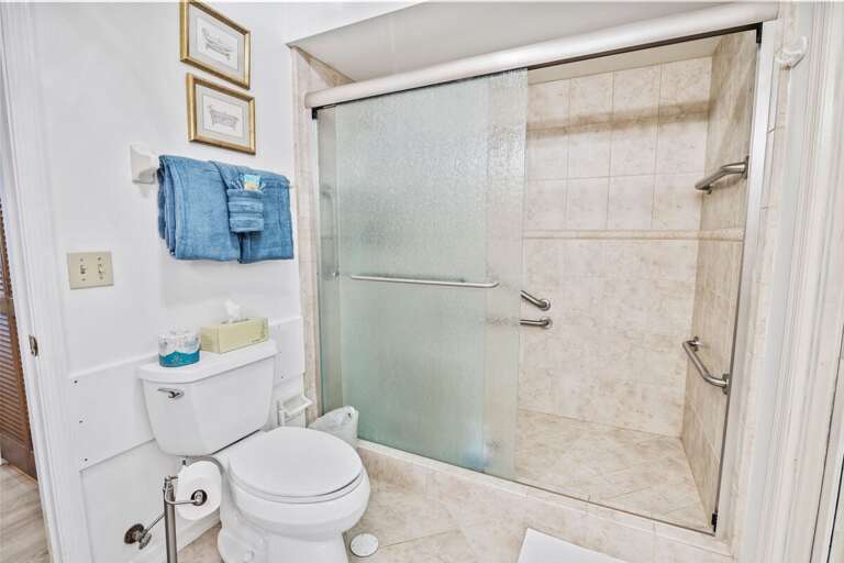 Bright bathroom with a spacious walk-in shower, safety grab bars, and fresh towels. Designed for
