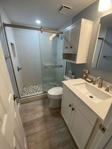 Clean and modern bathroom in this relaxing beach stay featuring a spacious walk-in glass shower, updated vanity, and bright lighting. A refreshing space to start or end your perfect day at the beach.