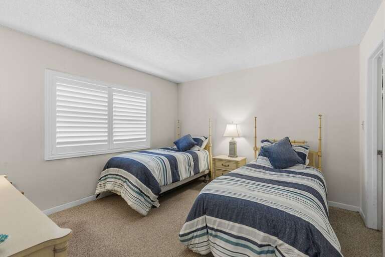 This inviting twin bedroom offers a cozy retreat with comfortable bedding and a bright, relaxing