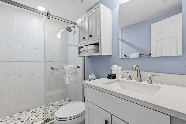 Refresh in this modern coastal bathroom featuring a sleek walk-in shower, bright finishes, and spa-like comfort. Perfect for a relaxing beach stay after a day spent enjoying the sun and ocean breeze.