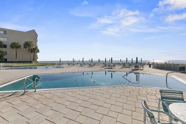 Unwind at the beachfront resort pool with panoramic ocean views, lounge seating, and direct beach