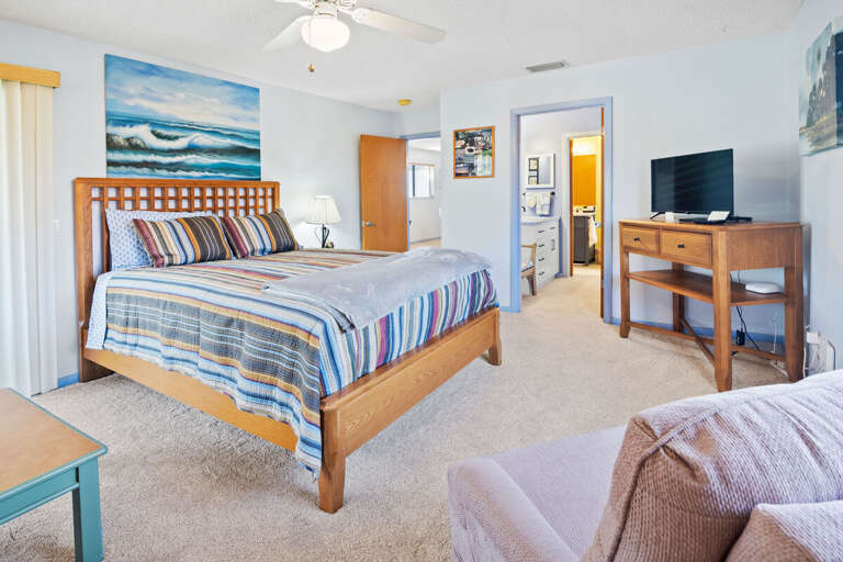 Unwind in this spacious beach stay bedroom featuring a comfortable bed, coastal décor, and soft