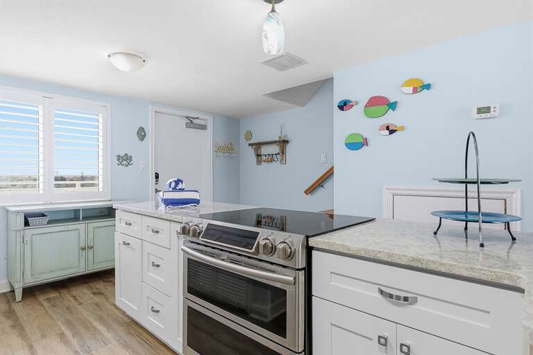 Enjoy this cheerful beach stay kitchen featuring a spacious island, modern appliances, and coastal décor. A perfect spot for cooking, gathering, and relaxing after a fun day by the beach.