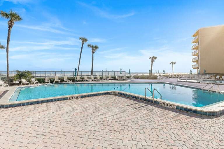 Enjoy a refreshing swim in the spacious beachfront pool surrounded by lounge seating and palm trees.