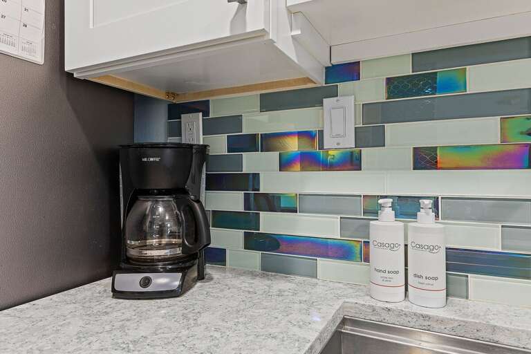Start your beach stay with a fresh cup of coffee in this stylish coastal kitchen. Featuring modern finishes and a colorful backsplash, it's the perfect spot to ease into your seaside mornings.
