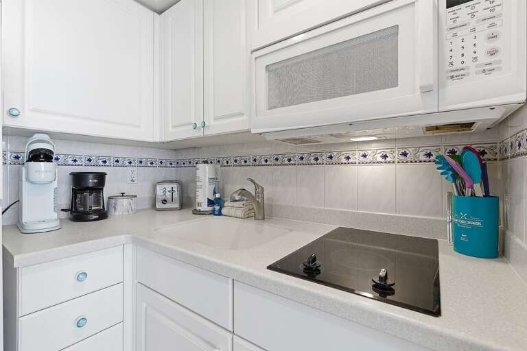 Well-equipped beach stay kitchenette featuring a cooktop, microwave, coffee maker, and essentials for easy meal prep. Enjoy the convenience of home while relaxing at your coastal getaway.