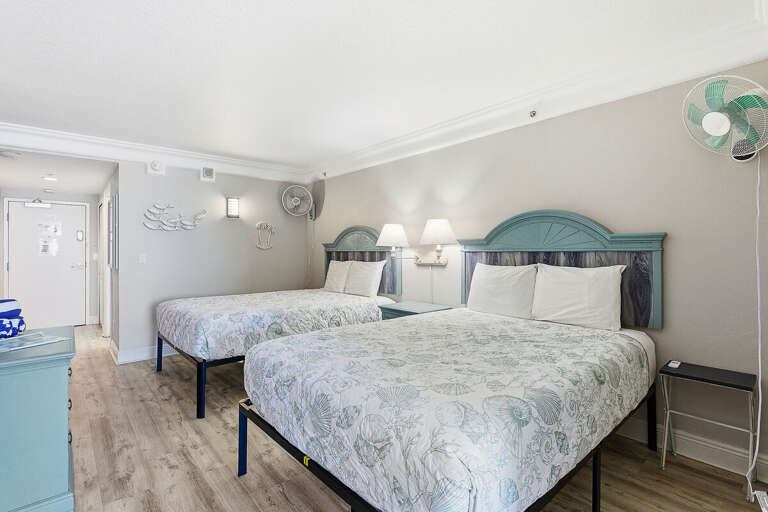 Relax in this inviting beach stay bedroom featuring two cozy beds, coastal décor, and plenty of space to unwind. Perfect for families or friends after a fun day enjoying the nearby beach and ocean.
