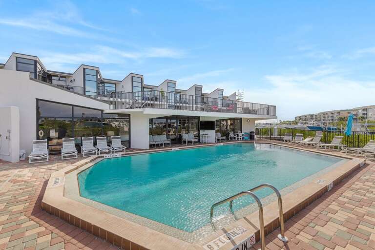 Enjoy a relaxing beach stay with this spacious waterfront pool deck, featuring lounge chairs, shaded