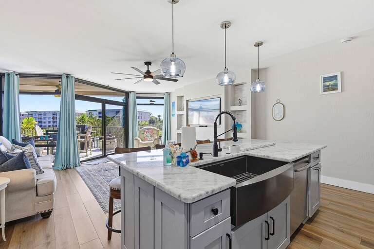 Enjoy your beach stay in this bright coastal kitchen featuring a large island, farmhouse sink, and