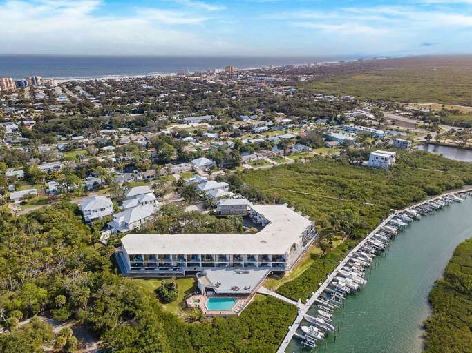 Experience the ultimate beach stay with this aerial view of a waterfront condo, marina, and nearby