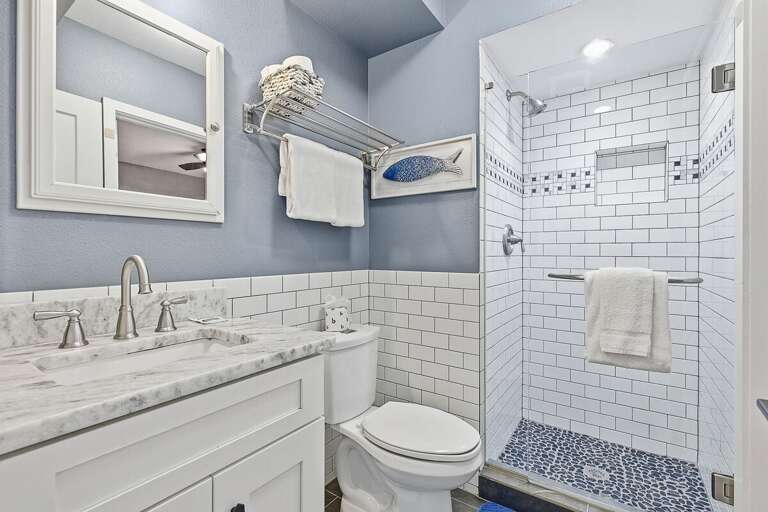 Refresh during your beach stay in this stylish bathroom featuring a walk-in tiled shower, modern