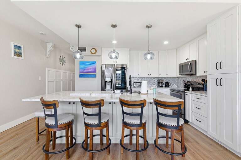 This beach stay features a bright, modern kitchen with a large island, bar seating, and updated