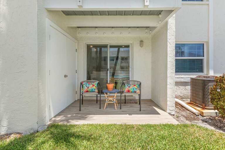 Enjoy morning coffee or evening relaxation on this private beach stay patio with comfortable seating and easy pool access—perfect for soaking up the coastal atmosphere near the beach.