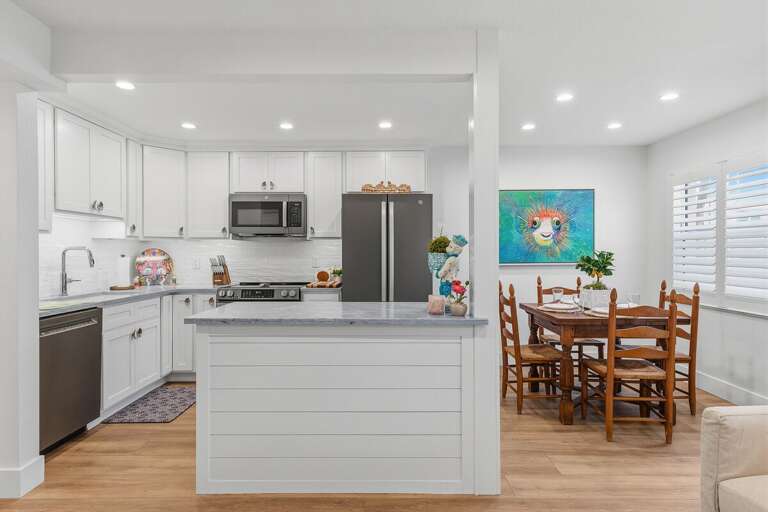 Enjoy a stylish beach stay with this updated kitchen and cozy dining area featuring bright coastal touches, modern appliances, and an open layout perfect for gathering after a day by the beach.