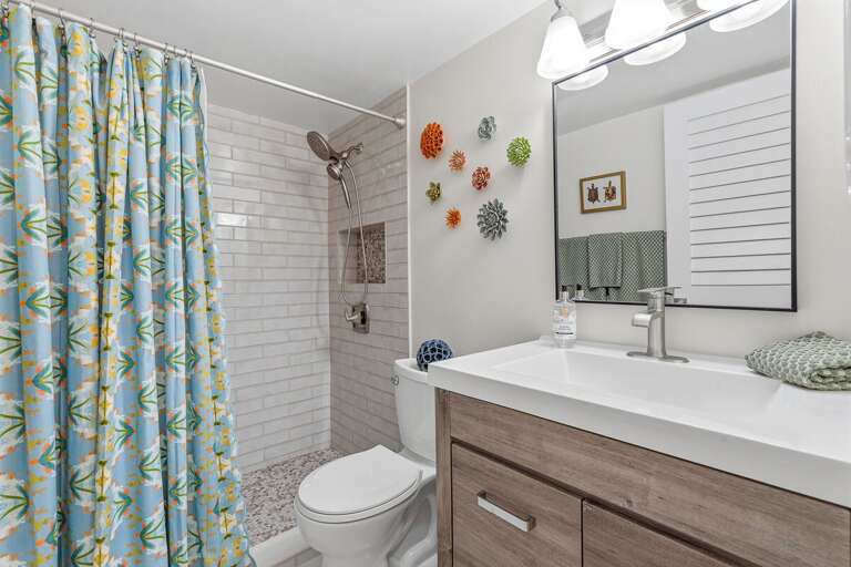Refresh after a beach day in this stylish coastal bathroom featuring a modern walk-in shower, bright finishes, and beach-inspired décor for a relaxing and comfortable beach stay.