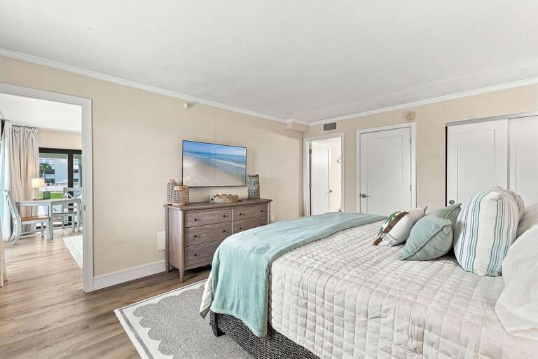 Wake up refreshed in this serene king bedroom featuring a plush bed, coastal décor, and a TV for