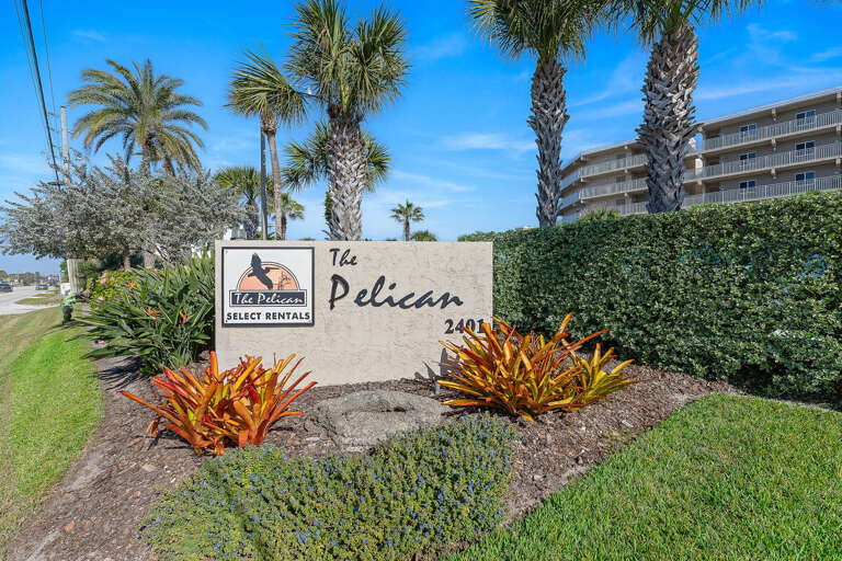 Arrive at The Pelican, a welcoming coastal retreat surrounded by lush tropical landscaping and palm trees—setting the scene for a relaxing and memorable New Smyrna Beach stay.