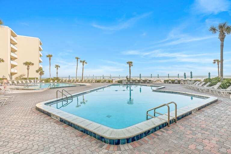 Soak up the Florida sunshine at the spacious oceanfront pool, surrounded by lounge seating, palm trees, and refreshing coastal views—the perfect spot to relax and recharge during your beach stay.