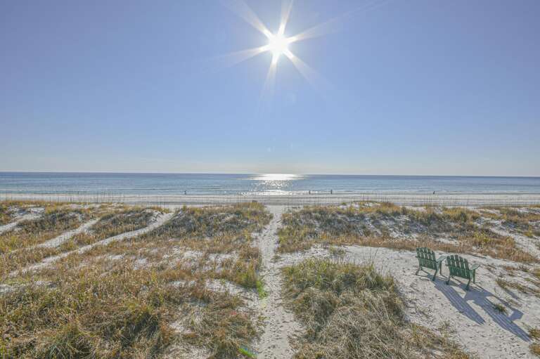 Sunlit beach path leading to sparkling ocean views