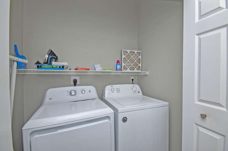 Bright, efficient laundry room with modern appliances and storage shelf