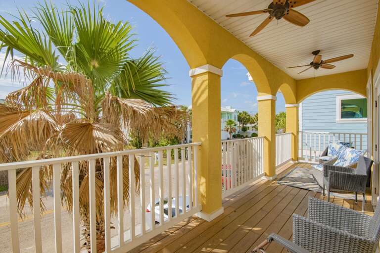 Sunny covered balcony with ceiling fans and tropical views