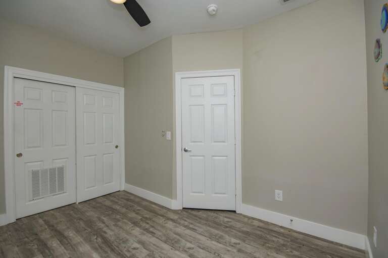 Cozy, bright bedroom with modern flooring and ceiling fan
