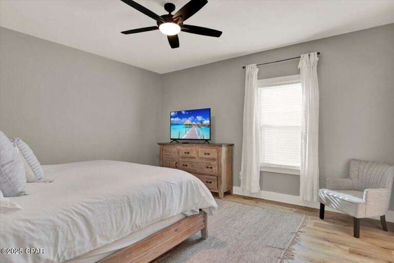 Bright and airy bedroom with cozy seating and modern ceiling fan