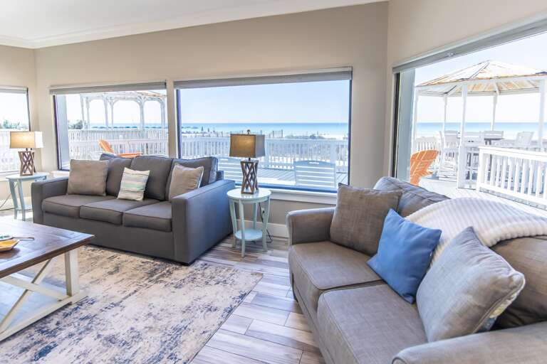 Sunlit living room with panoramic waterfront views and cozy seating