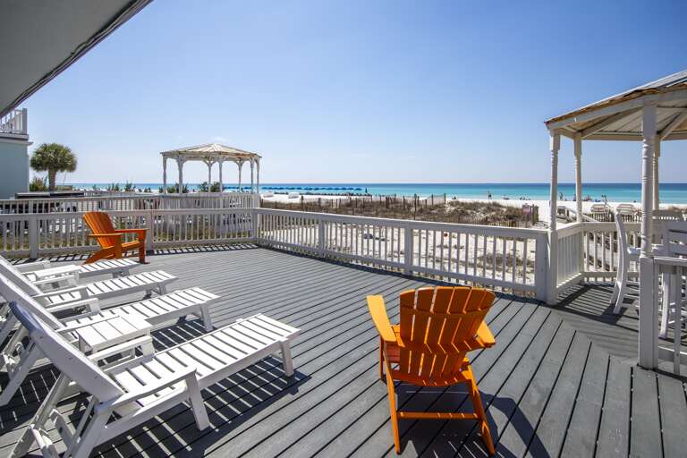 Spacious oceanfront deck with panoramic beach views and cozy seating
