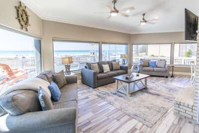 Spacious living room with panoramic waterfront views and cozy seating.