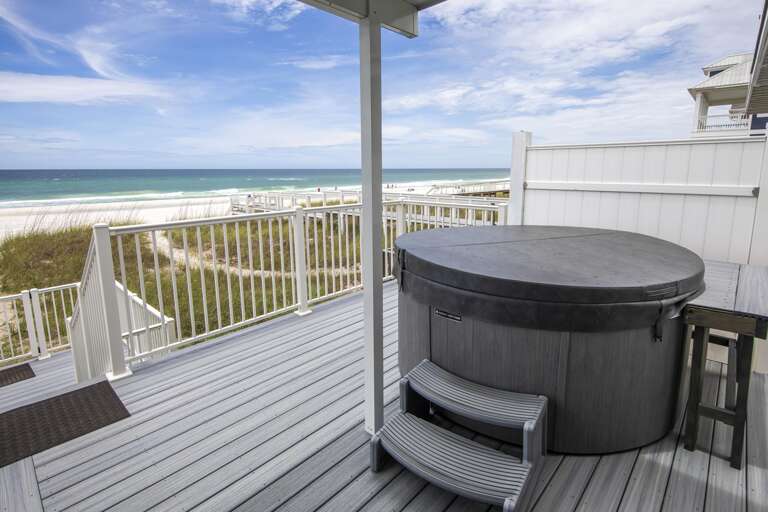 Beachfront deck with gray composite flooring, white railings, and a covered hot tub overlooking the ocean.