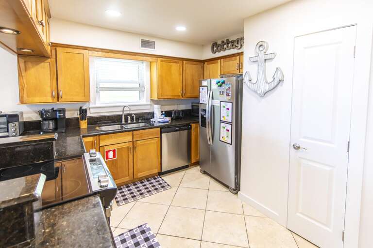 Kitchen with honey oak cabinets, black granite countertops, stainless steel appliances, and tiled floor.