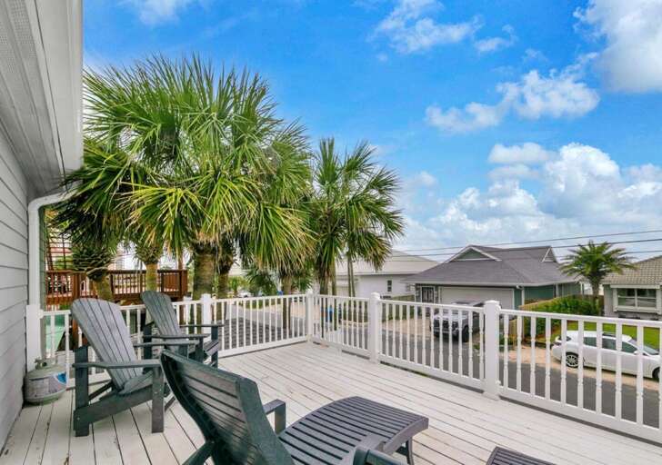 Spacious sunlit deck with cozy seating and palm views