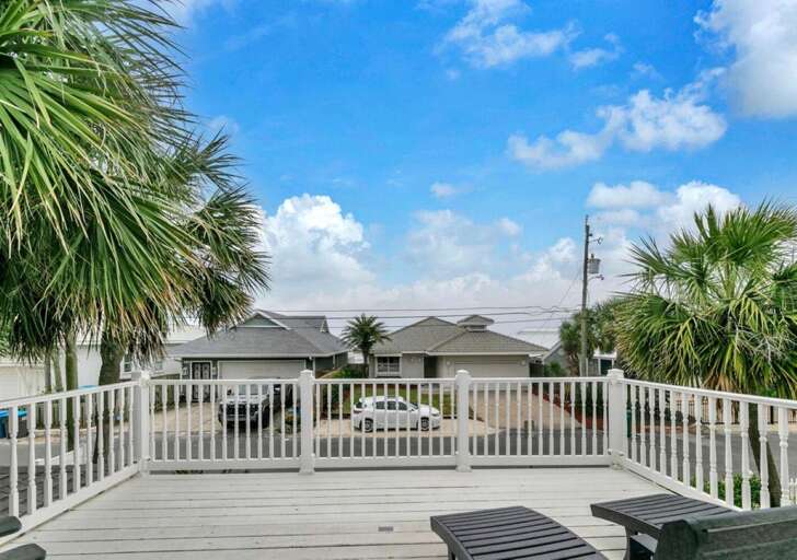 Spacious sunlit deck with ocean views and palm trees