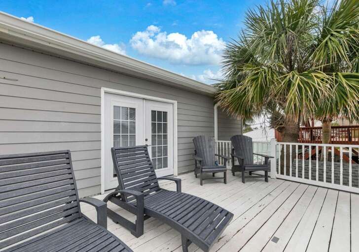Sunny outdoor deck with comfortable lounge seating and palm tree views