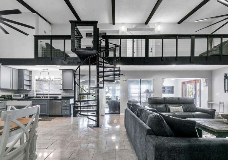 Spacious living room with modern spiral staircase and loft view