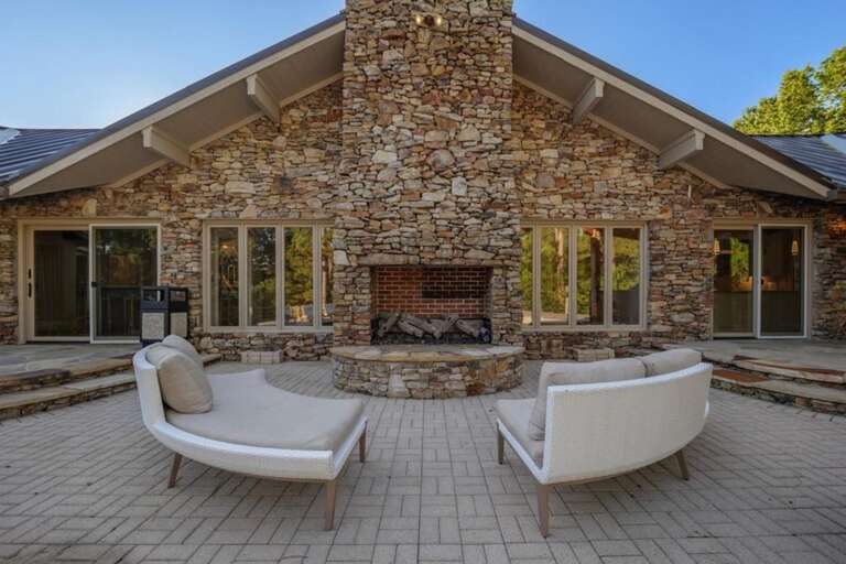 Spacious outdoor patio with cozy stone fireplace and seating
