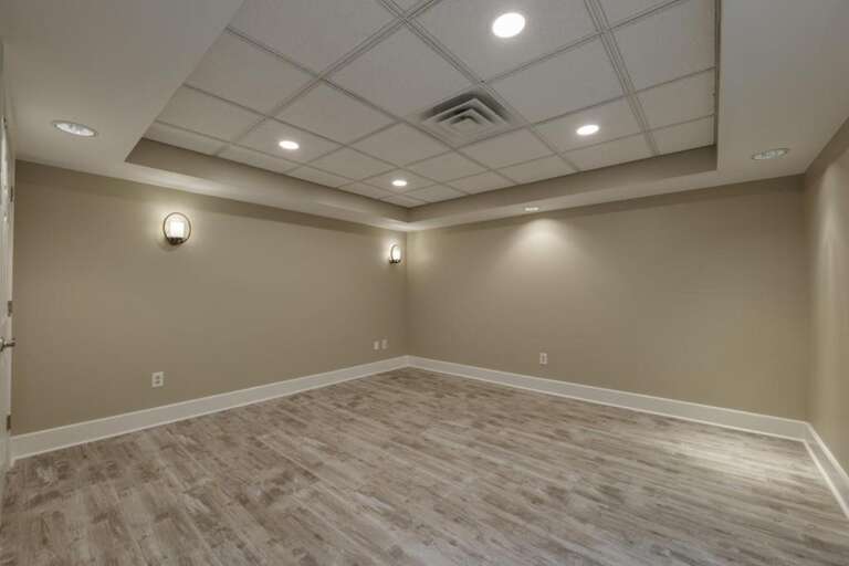 Spacious, serene basement retreat with modern lighting and flooring