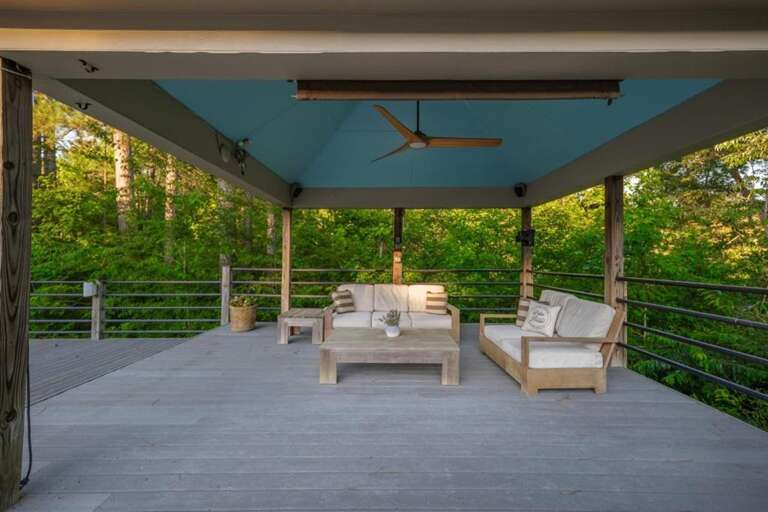 Spacious covered deck with cozy seating and forest views