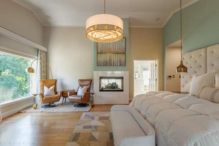 Sunlit bedroom retreat with cozy fireplace and seating nook