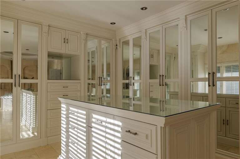 Sunlit dressing room with ample storage and elegant mirrors