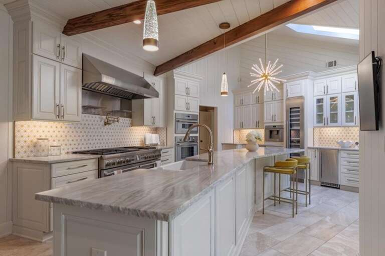 Spacious kitchen with marble island and rustic beam accents