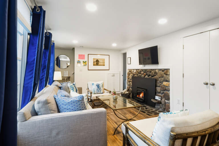 Living room with woodstove, smart tv, and open to the dining room. 