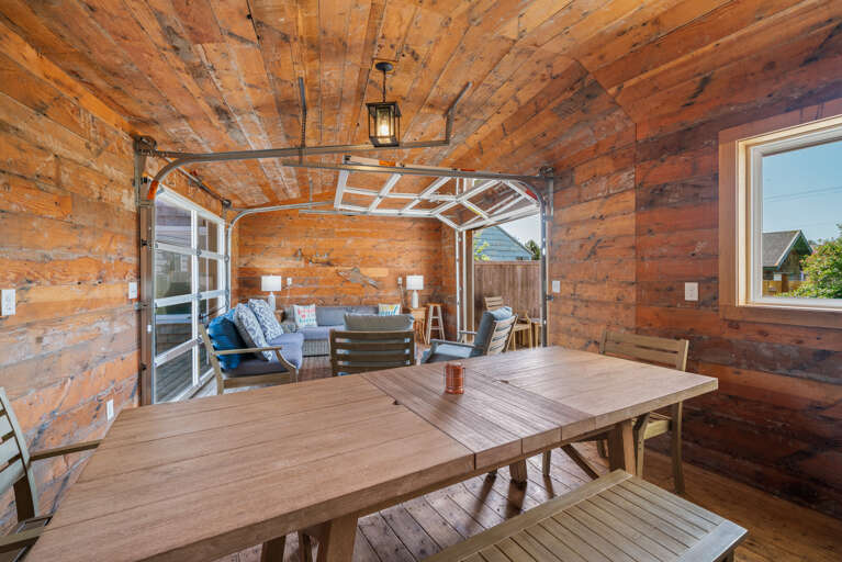 Outdoor living space with covered lounging furniture, streaming TV, dining area, open to back yard with BBQ. 