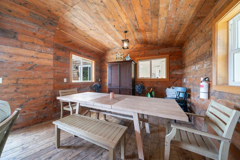 Outdoor living space with covered lounging furniture, streaming TV, dining area, open to back yard with BBQ. 