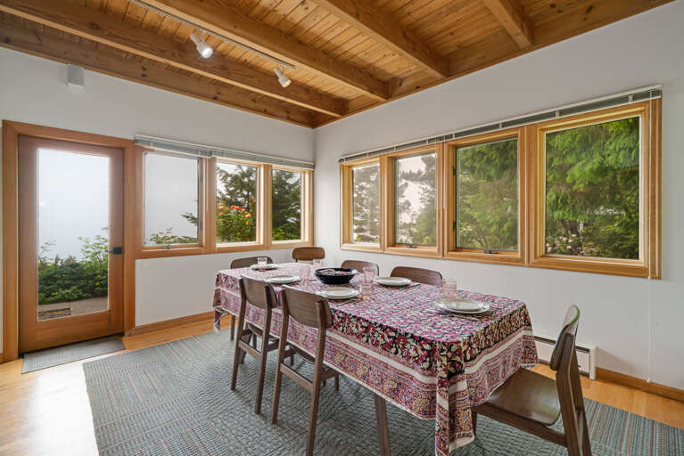 Dining room with additional bench seating, Ocean views, and access to the fenced yard area.