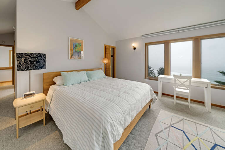 Master bedroom with a king bed, desk area, lounging chair, walk in closet, and master bath with sit down shower and dual sinks with spectacular views. 