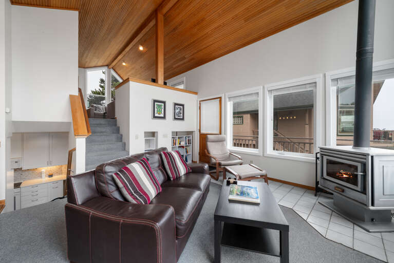 Open living and dining area with wood stove, access to oceanview deck. 