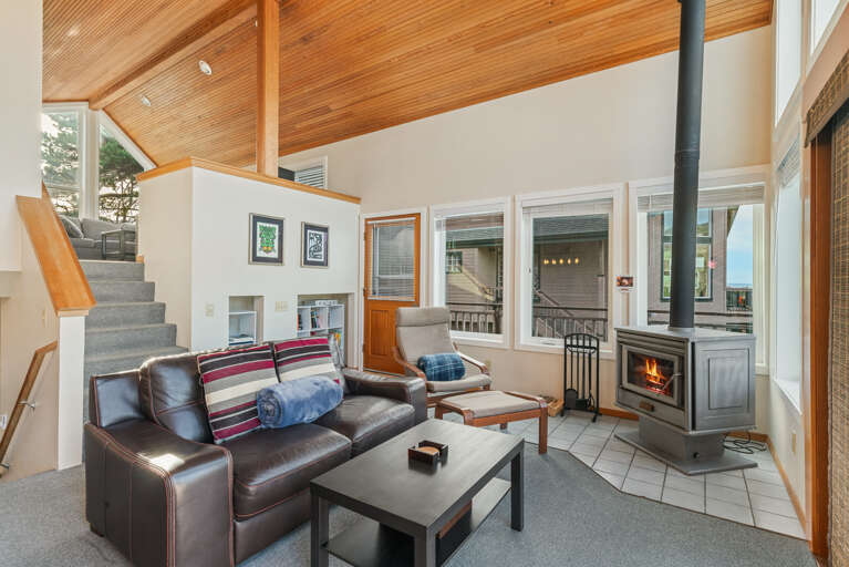 Living/dining room with woodstove and access to front deck with BBQ and outdoor furniture.